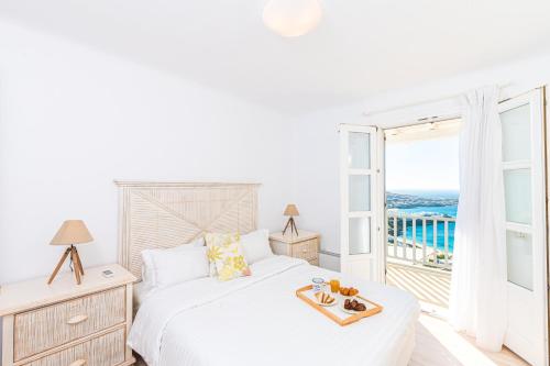 a white bedroom with a bed and a balcony at Villa Thelgo Mykonos in Psarou