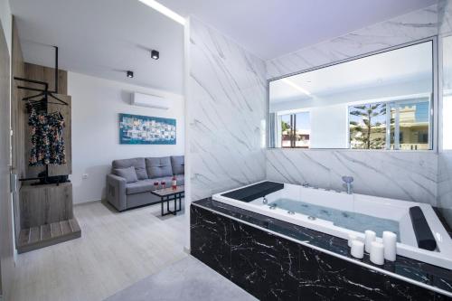 ein großes Bad mit einer Badewanne und einer Couch in der Unterkunft xSuites in Agia Marina