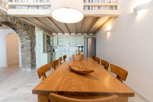 a dining room with a wooden table and chairs at Villa Thelgo Mykonos in Psarou