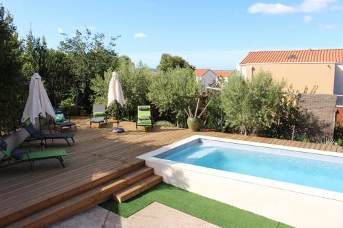une terrasse en bois avec une piscine, des chaises et des soins dans l'établissement Le Terracotta , 2chambres, Terrasse, Piscine, Parking gratuit, Wifi, Climatisation, à Marseillan
