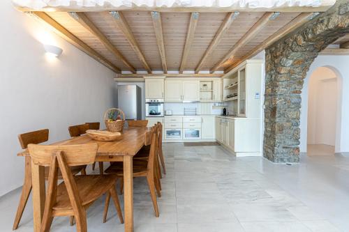 a dining room with a wooden table and chairs at Villa Thelgo Mykonos in Psarou