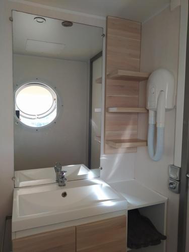 W łazience znajduje się umywalka i lustro. w obiekcie Camping Les Peupliers w mieście Saint-Père-en-Retz
