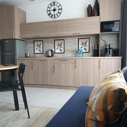 une cuisine avec des armoires en bois et une horloge au mur dans l'établissement Q Apart AMBER - klimatyzowane STUDIO przy Manufakturze z garażem Gratis, FV, à Łódź