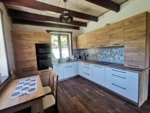 a kitchen with white cabinets and a wooden floor at DoMarka całoroczny dom w Bieszczadach in Wetlina