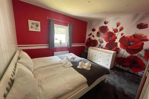 een slaapkamer met een bed met rode muren en bloemen aan de muur bij Murzeit Apartman in Murau