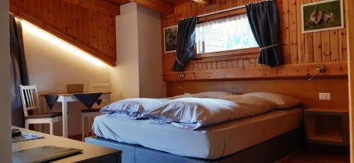 a bed in a room with a window at La Pineta Apartment in Padola