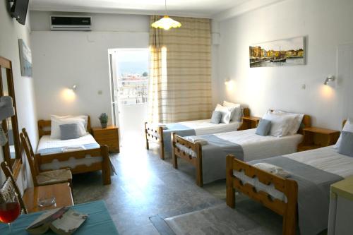 a hotel room with three beds and a table at Klinakis Beach Hotel in Chania Town