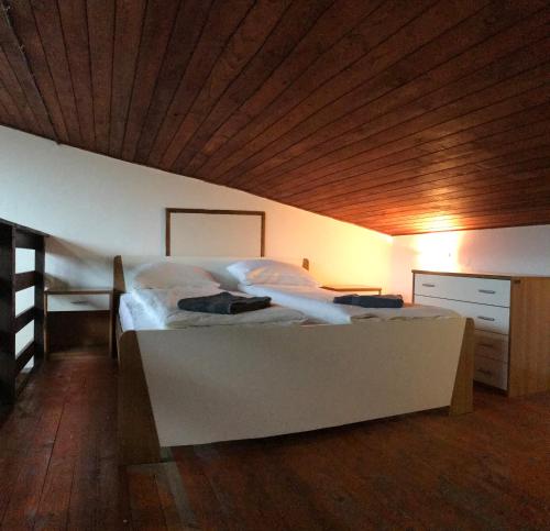 a bedroom with a white bed with a wooden ceiling at Apartmani Košuta in Tjentište