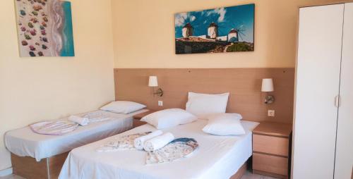 two beds in a hotel room with white sheets at Jimmy's rooms nea potidea in Nea Potidaea