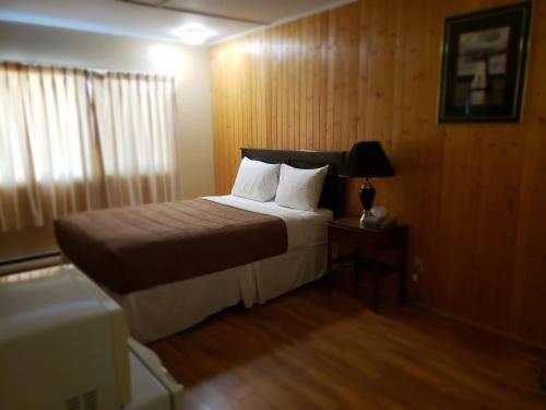 a bedroom with a bed and a lamp on a table at Wildwood Motel in Shelburne