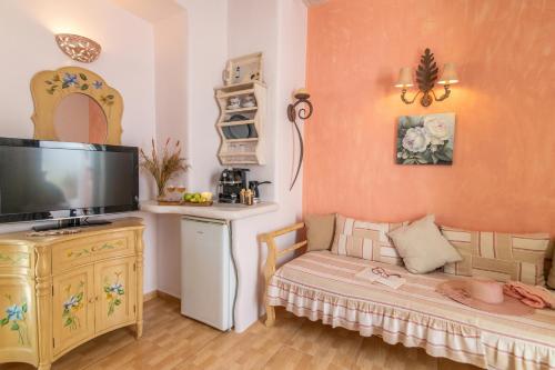 a living room with a couch and a flat screen tv at Madalena's Family Rooms in Tinos