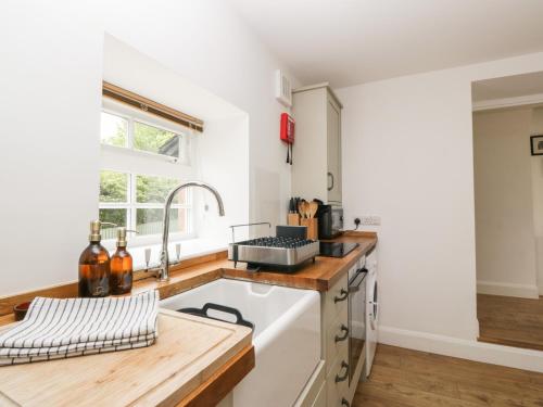 a kitchen with white cabinets and a sink at Ellanderroch in Glasgow