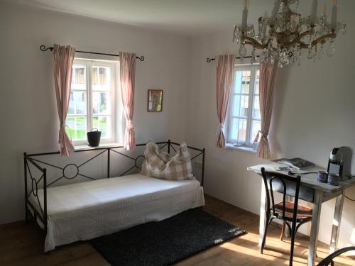 a bedroom with a bed and a desk and windows at Kellerstöckl am veganen Bio-Lebenshof "Varm - die vegane Farm" in Bergla