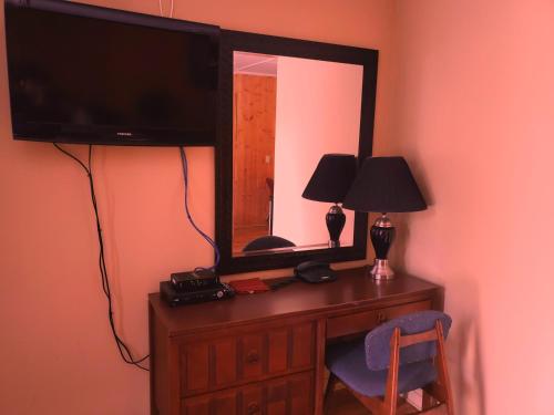 a desk with a television and a mirror on a wall at Wildwood Motel in Shelburne