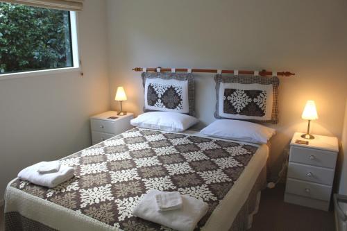 a bedroom with a large bed with two lamps at Parsloe's Cottage in Coromandel Town