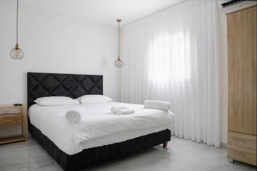 a white bedroom with a large bed with white sheets at צופית דירות אירוח 2 דירות, האחת חדר שינה וסלון והשניה 2 חדרי שינה וסלון in Eilat