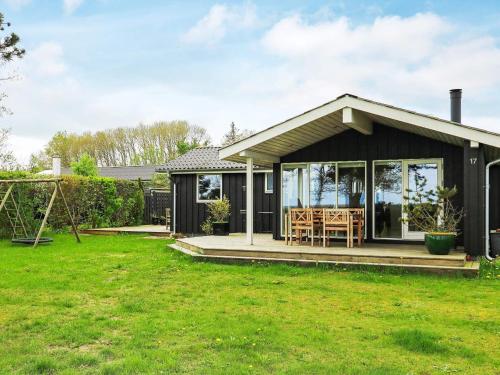 Ce petit cottage noir dispose d'une terrasse couverte et d'une balançoire. dans l'établissement 9 person holiday home in Hadsund, à Nørre Hurup