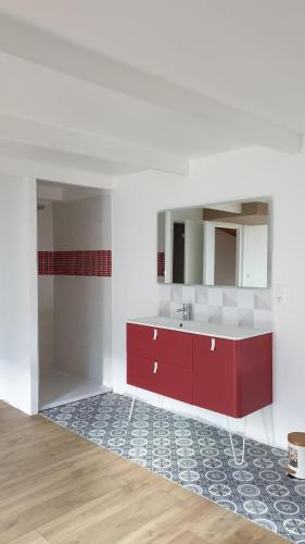 La salle de bains est pourvue d'un lavabo rouge et d'un miroir. dans l'établissement Le Mas des Lucioles à Vinezac, à Vinezac