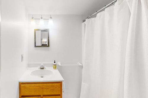 a bathroom with a white shower curtain and a sink at The Treehouse at 10th in Folly Beach