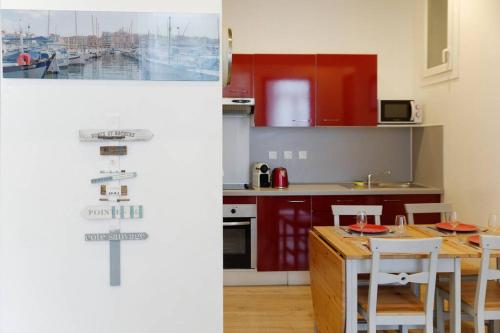 une cuisine avec des armoires rouges et une table et des chaises dans l'établissement SCHUMAN 2 - Le bonheur de la Joliette, à Marseille