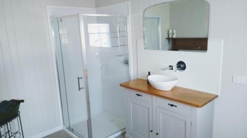 a white bathroom with a sink and a shower at The Gardener's Cottage on Warrentinna in Branxholm