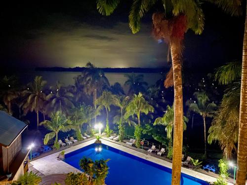 a view of a pool at night with palm trees at Villa Caribe in Lívingston
