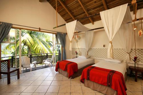 a bedroom with two beds and a balcony at Villa Caribe in Lívingston