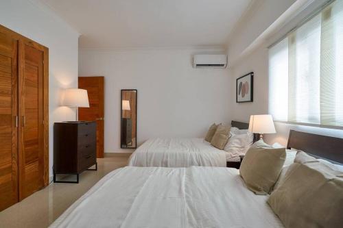a large white bedroom with two beds and a window at Escape Apartments, Balcony, Pool, Gym & Spa in La Julia in Santo Domingo