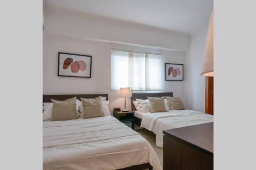 two beds in a room with white walls at Escape Apartments, Balcony, Pool, Gym & Spa in La Julia in Santo Domingo