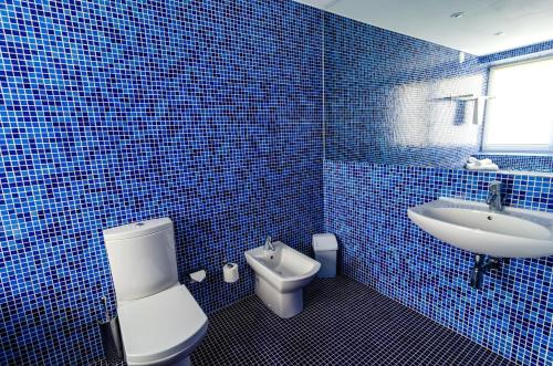 Baño de azulejos azules con aseo y lavamanos en Vilatekila-Lili Apartments, en Palanga