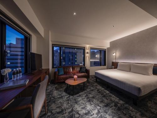 una camera d'albergo con letto, scrivania e finestra di THE LIVELY HONMACHI OSAKA / Vacation STAY 76687 ad Osaka