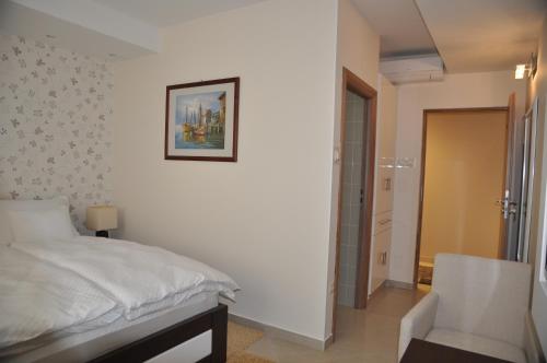biała sypialnia z łóżkiem i krzesłem w obiekcie Widder Rooms w mieście Osijek