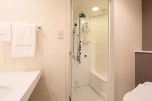 a white bathroom with a shower and a sink at Hiroshima Tokyu REI Hotel in Hiroshima