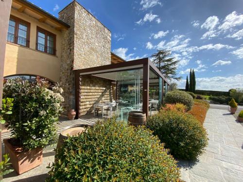 a house with glass doors and some bushes at Hotel Borgo Di Cortefreda - Place of Charme in Tavarnelle in Val di Pesa