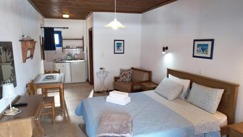 a bedroom with a bed and a desk and a kitchen at Egeon Studios in Neos Marmaras
