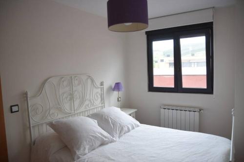 1 dormitorio con 1 cama blanca y ventana en Dúplex con soleada terraza!, en Renedo de Piélagos