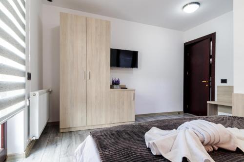 a bedroom with a bed and a tv on a wall at Agropensiunea Andrei & Ianis in Dăeşti