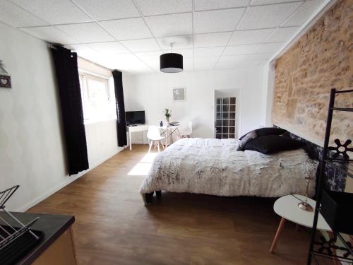 1 dormitorio con cama y pared de ladrillo en Appartement Jarnioux - Les Meublés des Pierres Dorées, en Theizé