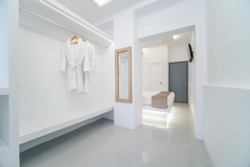 a white room with a bed and a mirror at Serenità Luxury Suites in Akrotiri
