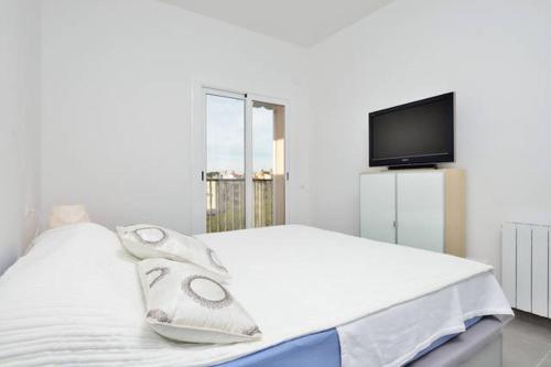 a white bedroom with a bed and a tv at COSY WELL SITUED APARTMENT WITH SEA VIEW in Vilanova i la Geltrú