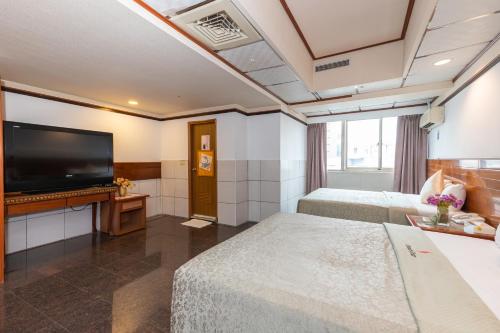 a hotel room with two beds and a flat screen tv at Yi Pin Business Hotel in Taoyuan