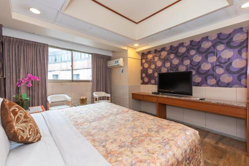 Yi Pin Business Hotel في تاويوان: غرفة فندقية بسرير وتلفزيون بشاشة مسطحة