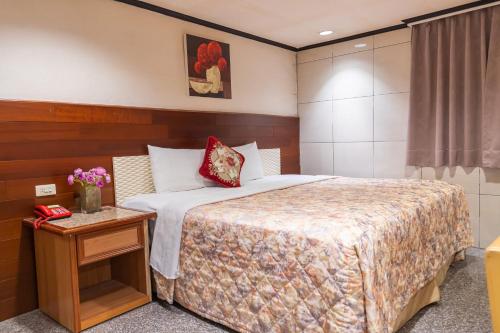 a hotel room with a bed and a table with flowers at Yi Pin Business Hotel in Taoyuan
