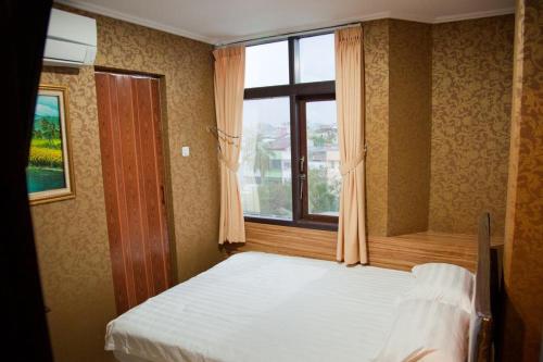 una camera con un letto bianco e una finestra di Hotel Rumah Shinta a Giacarta