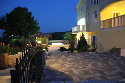 une maison avec une clôture devant elle la nuit dans l'établissement Apartments Villa Lora, à Kraj