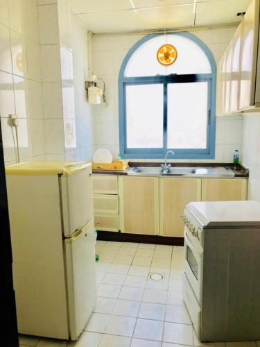 a kitchen with a window and a sink and a refrigerator at PAN Hotel Apartments in Sharjah