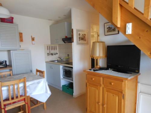 - une cuisine avec une télévision sur un plan de travail et une table dans l'établissement Maison T3 climatisée à barcares village, au Barcarès