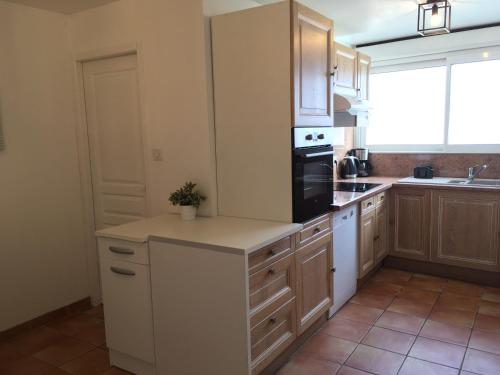 une cuisine avec des armoires blanches et un appareil noir dans l'établissement PYRENE HOLIDAYS - Résidence La Fontaine - Triplex spacieux à 10mn à pied des thermes, à Bagnères-de-Bigorre