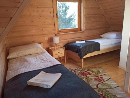 a bedroom with two beds in a log cabin at Domek 'Słoneczna 2' z RUSKĄ BANIĄ in Kluszkowce
