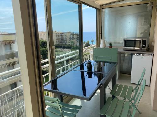 d'un balcon avec une table et des chaises en verre donnant sur l'océan. dans l'établissement Appartement rooftop, première ligne, vue mer, 50m de plage du Midi, à Cannes